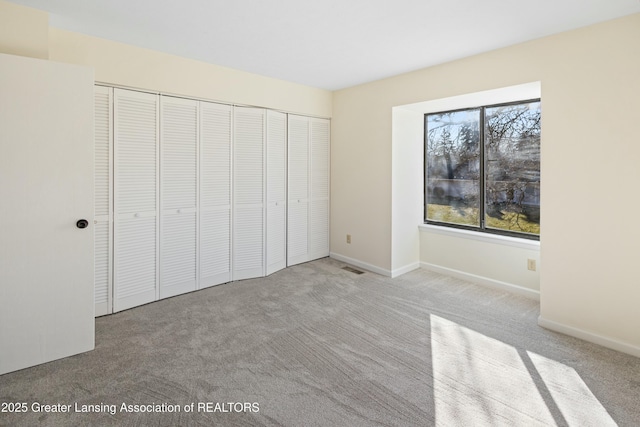 unfurnished bedroom featuring a closet, visible vents, baseboards, and carpet floors