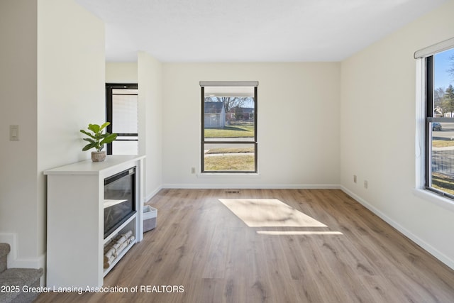 unfurnished living room featuring wine cooler, baseboards, plenty of natural light, and wood finished floors