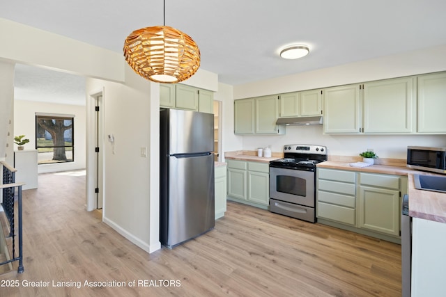 kitchen with under cabinet range hood, stainless steel appliances, light wood finished floors, green cabinetry, and hanging light fixtures