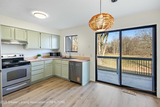 kitchen featuring visible vents, under cabinet range hood, light countertops, stainless steel appliances, and a sink