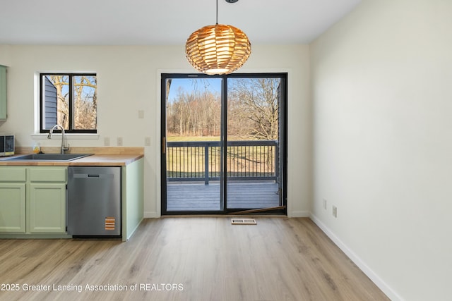 kitchen featuring a sink, light wood-style flooring, green cabinetry, and stainless steel appliances