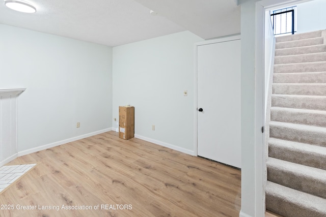 below grade area featuring stairway, wood finished floors, and baseboards