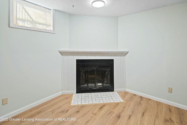 room details featuring baseboards, a textured ceiling, wood finished floors, and a tiled fireplace