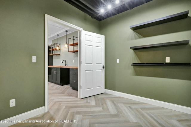 interior space featuring a sink, dark cabinetry, baseboards, and open shelves