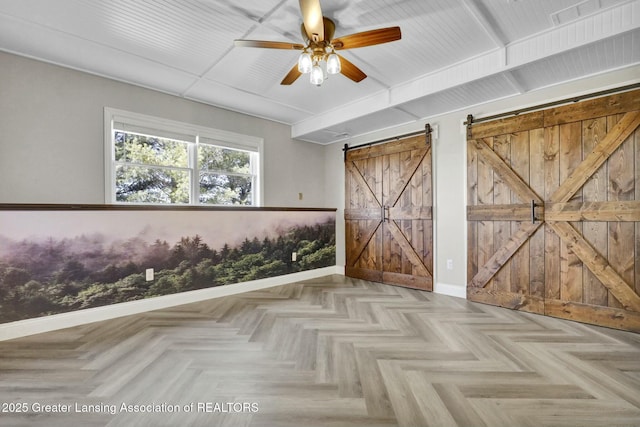 unfurnished bedroom with ceiling fan, baseboards, and a barn door