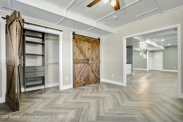 unfurnished bedroom featuring ceiling fan, baseboards, and a barn door