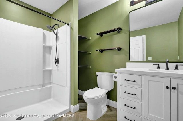 bathroom featuring vanity, toilet, baseboards, and walk in shower