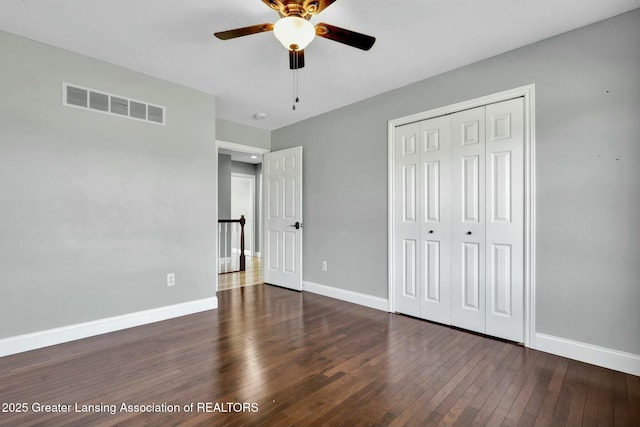 unfurnished bedroom with a closet, visible vents, baseboards, and hardwood / wood-style flooring