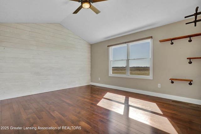 unfurnished room featuring baseboards, hardwood / wood-style floors, a ceiling fan, and vaulted ceiling