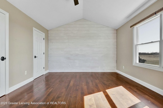 unfurnished room featuring dark wood finished floors, baseboards, and vaulted ceiling