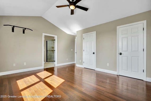 unfurnished bedroom with connected bathroom, ceiling fan, baseboards, lofted ceiling, and hardwood / wood-style flooring