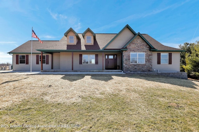 view of front of property featuring a front lawn, stone siding, and a shingled roof