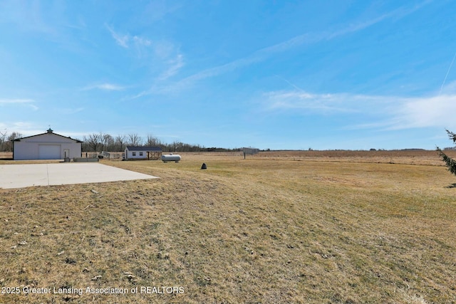 view of yard with an outbuilding, a rural view, and a detached garage