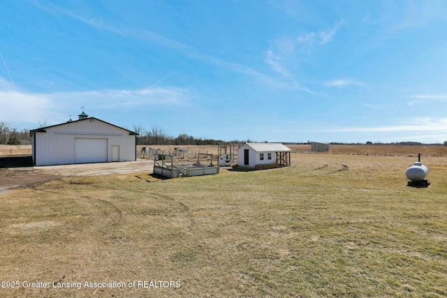 view of yard with an outbuilding, a rural view, and a garden