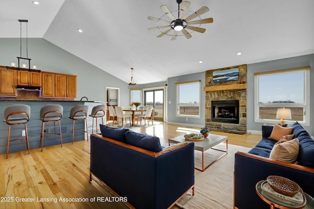 living room with recessed lighting, high vaulted ceiling, a fireplace, and light wood finished floors