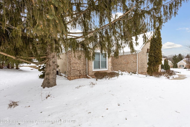 view of snowy exterior featuring brick siding