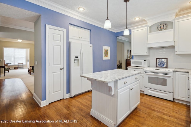 kitchen featuring white appliances, ornamental molding, a center island, and white cabinetry