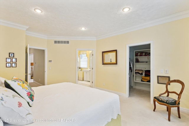 bedroom with visible vents, light carpet, a walk in closet, and crown molding