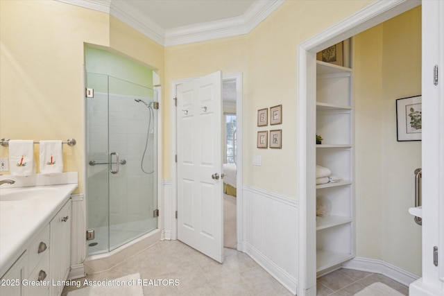 ensuite bathroom with tile patterned floors, built in shelves, ornamental molding, a shower stall, and vanity