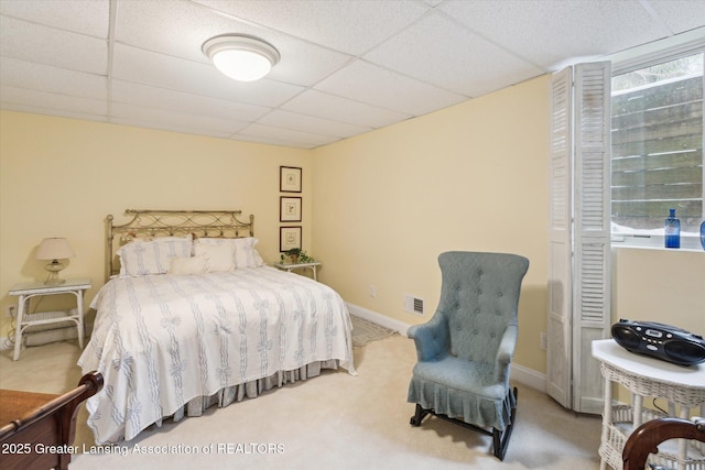 carpeted bedroom with visible vents, a paneled ceiling, and baseboards