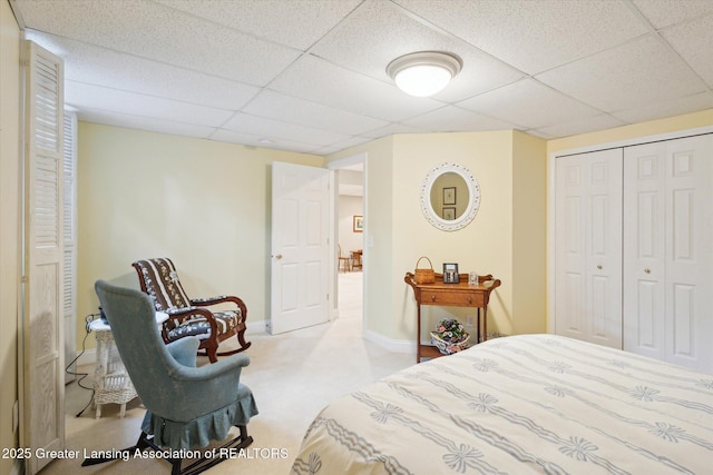 carpeted bedroom featuring a closet, a paneled ceiling, and baseboards