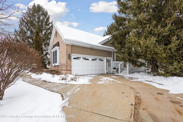 snow covered property featuring concrete driveway and a garage