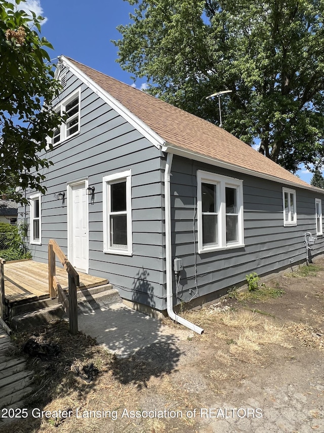 exterior space with a wooden deck and a shingled roof