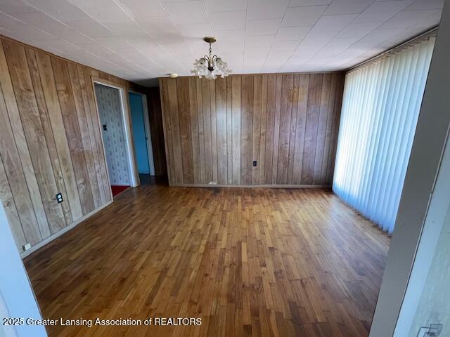 unfurnished dining area featuring baseboards, wood finished floors, and a chandelier