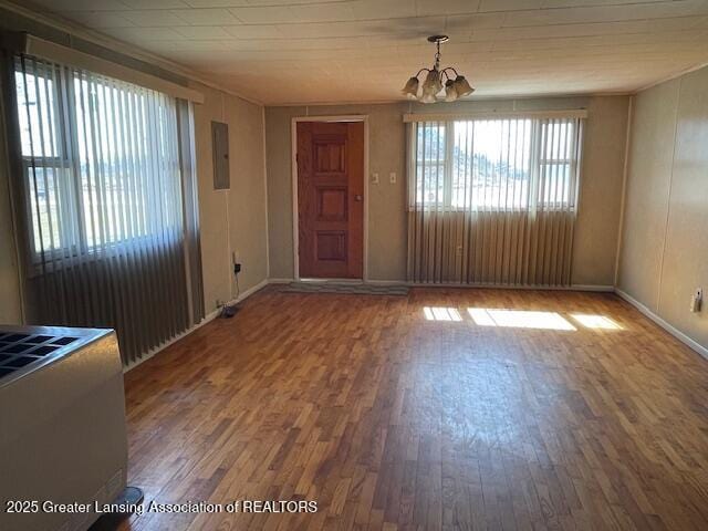 foyer with electric panel, baseboards, a notable chandelier, and wood finished floors