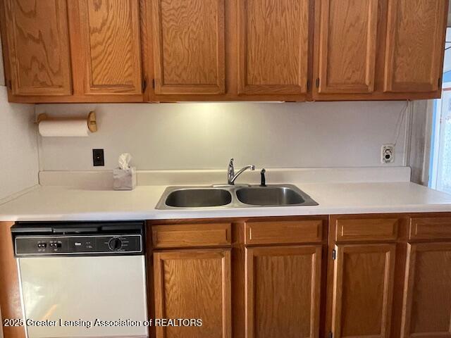 kitchen with a sink, dishwasher, brown cabinetry, and light countertops