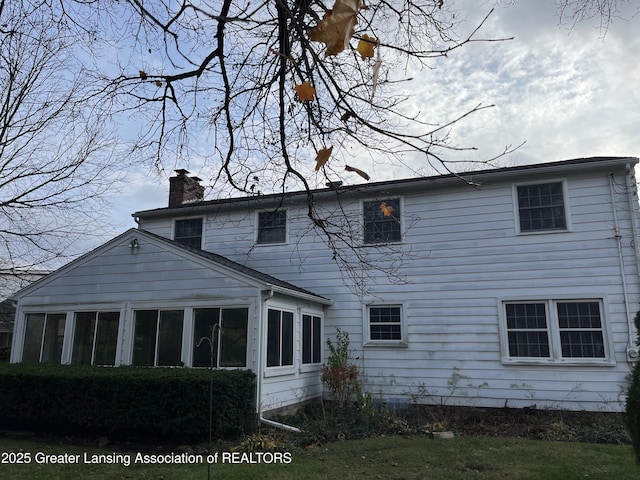 rear view of property with a sunroom and a chimney