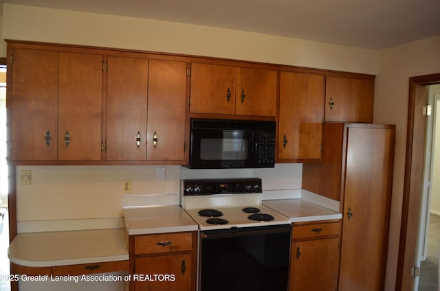 kitchen with brown cabinets, black microwave, and range with electric stovetop