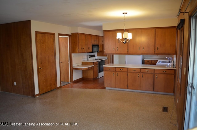 kitchen featuring white electric stove, black microwave, brown cabinetry, and light countertops