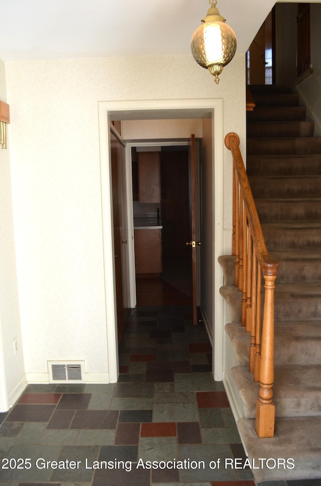 hall with visible vents, baseboards, and stairs