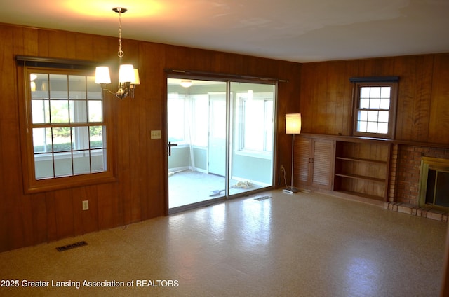 unfurnished living room with visible vents, wooden walls, and a fireplace