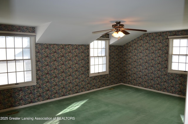 carpeted spare room featuring visible vents, a ceiling fan, baseboards, wallpapered walls, and lofted ceiling