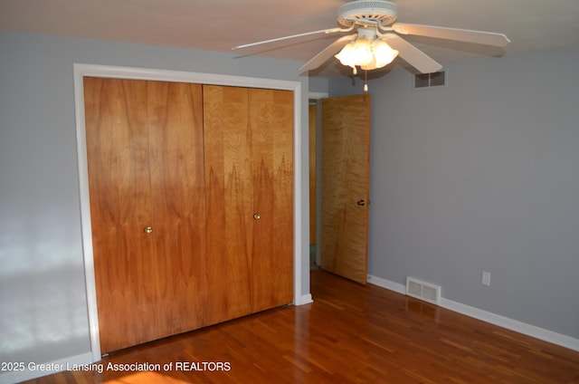 unfurnished bedroom featuring visible vents, baseboards, a closet, and wood finished floors