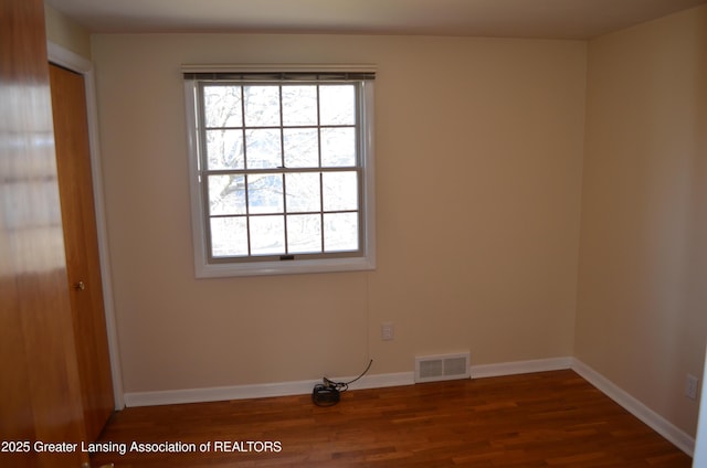 spare room with visible vents, baseboards, and wood finished floors