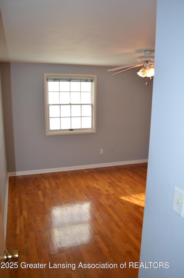 unfurnished room with wood finished floors, baseboards, and ceiling fan