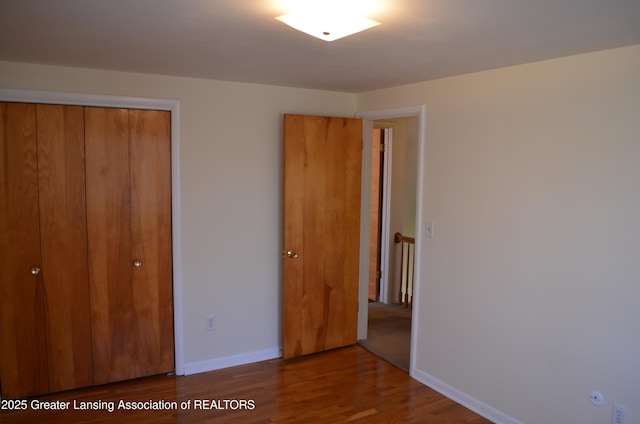 unfurnished bedroom with wood finished floors, a closet, and baseboards