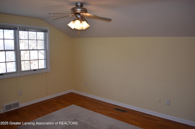 spare room featuring lofted ceiling, wood finished floors, and visible vents