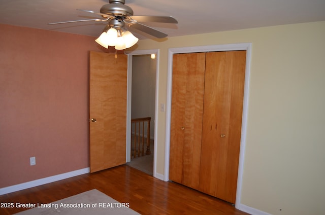 unfurnished bedroom featuring a closet, baseboards, wood finished floors, and a ceiling fan