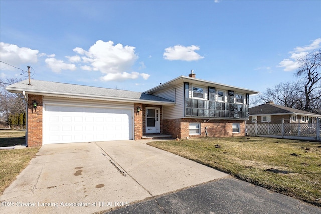 split level home with fence, concrete driveway, an attached garage, a front yard, and brick siding