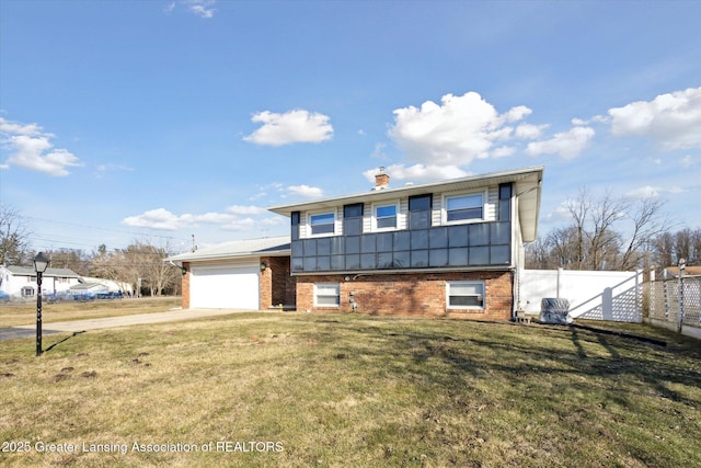 tri-level home featuring brick siding, a front lawn, fence, driveway, and an attached garage