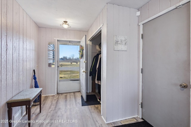 entrance foyer with wooden walls and light wood-style flooring