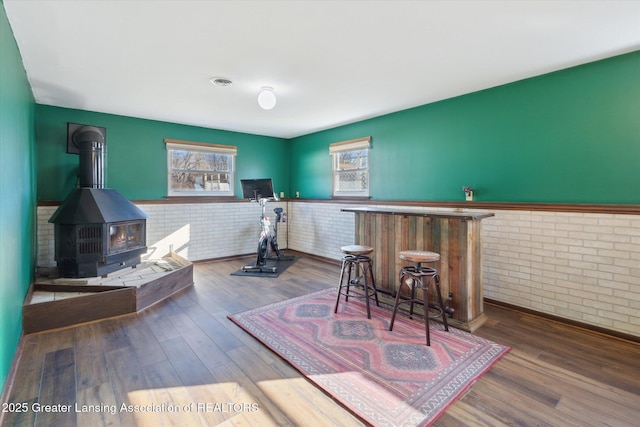 interior space featuring a dry bar, wood finished floors, visible vents, and a wood stove