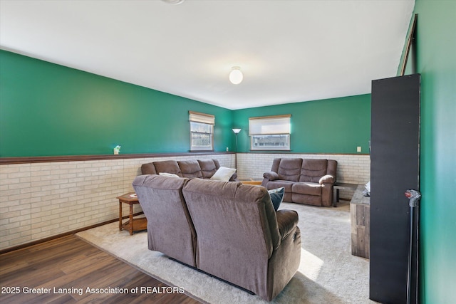 living room featuring brick wall, wood finished floors, and wainscoting