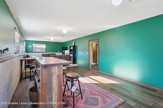 kitchen with a wainscoted wall, a kitchen breakfast bar, and wood finished floors