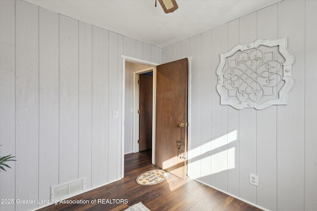 empty room with wood finished floors, visible vents, and ceiling fan