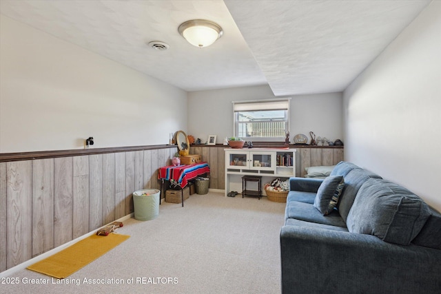 game room with wooden walls, visible vents, carpet, and a wainscoted wall